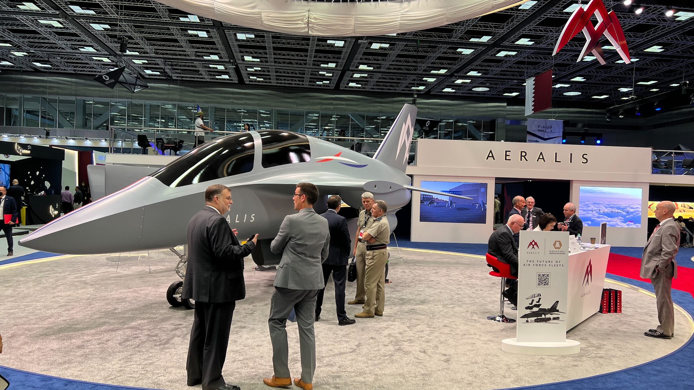 Visitors talk with members of the AERALIS team in front of a grey AERALIS jet